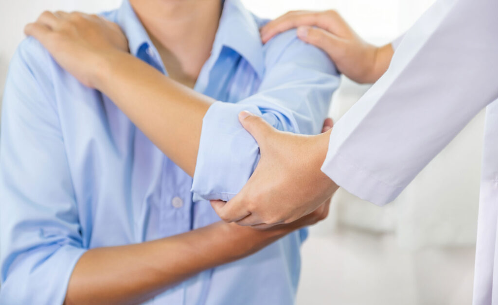 Arm &Amp; Elbow: Finding The Right Elbow Surgeon 1 A person holding their elbow in discomfort, representing arm and elbow pain treatment options.